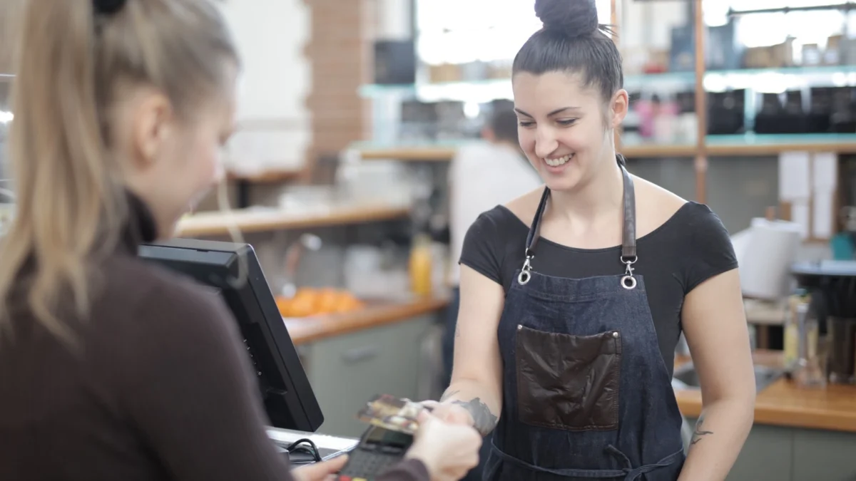 Customer making a contactless card payment at a cafe counter